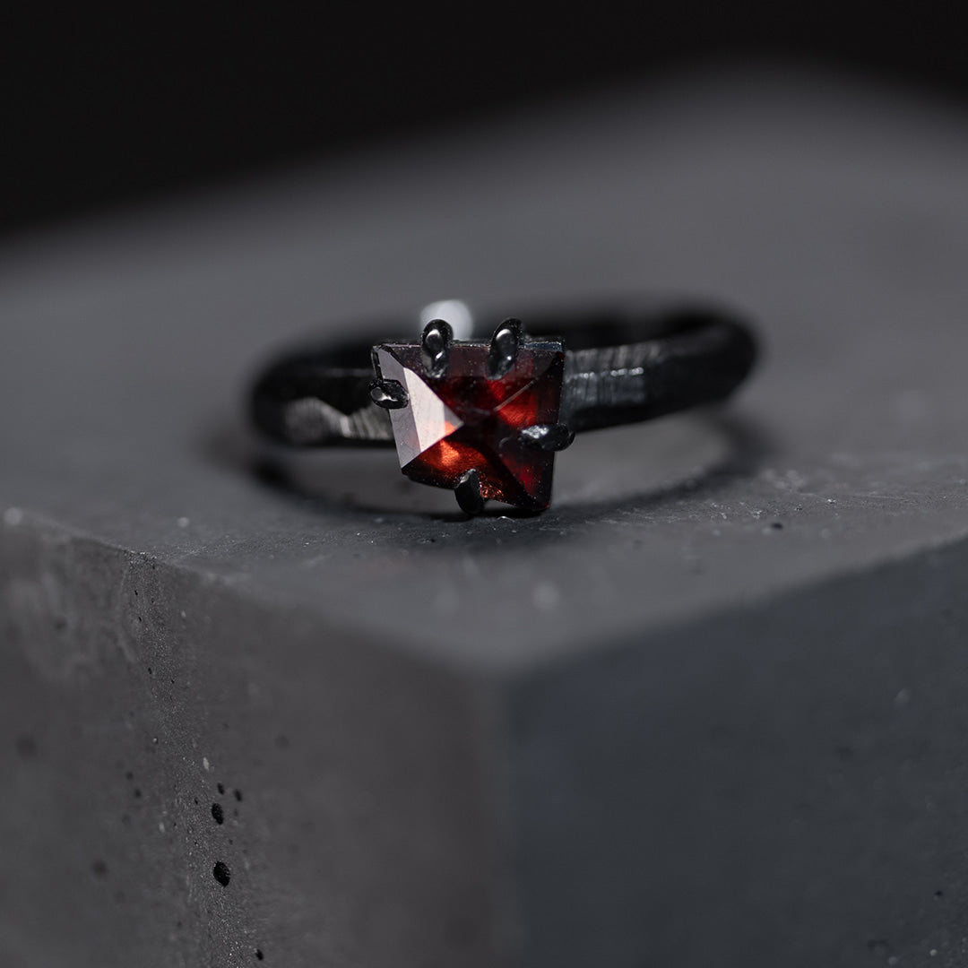 bague de fiançailles en or noir avec un grenat rouge