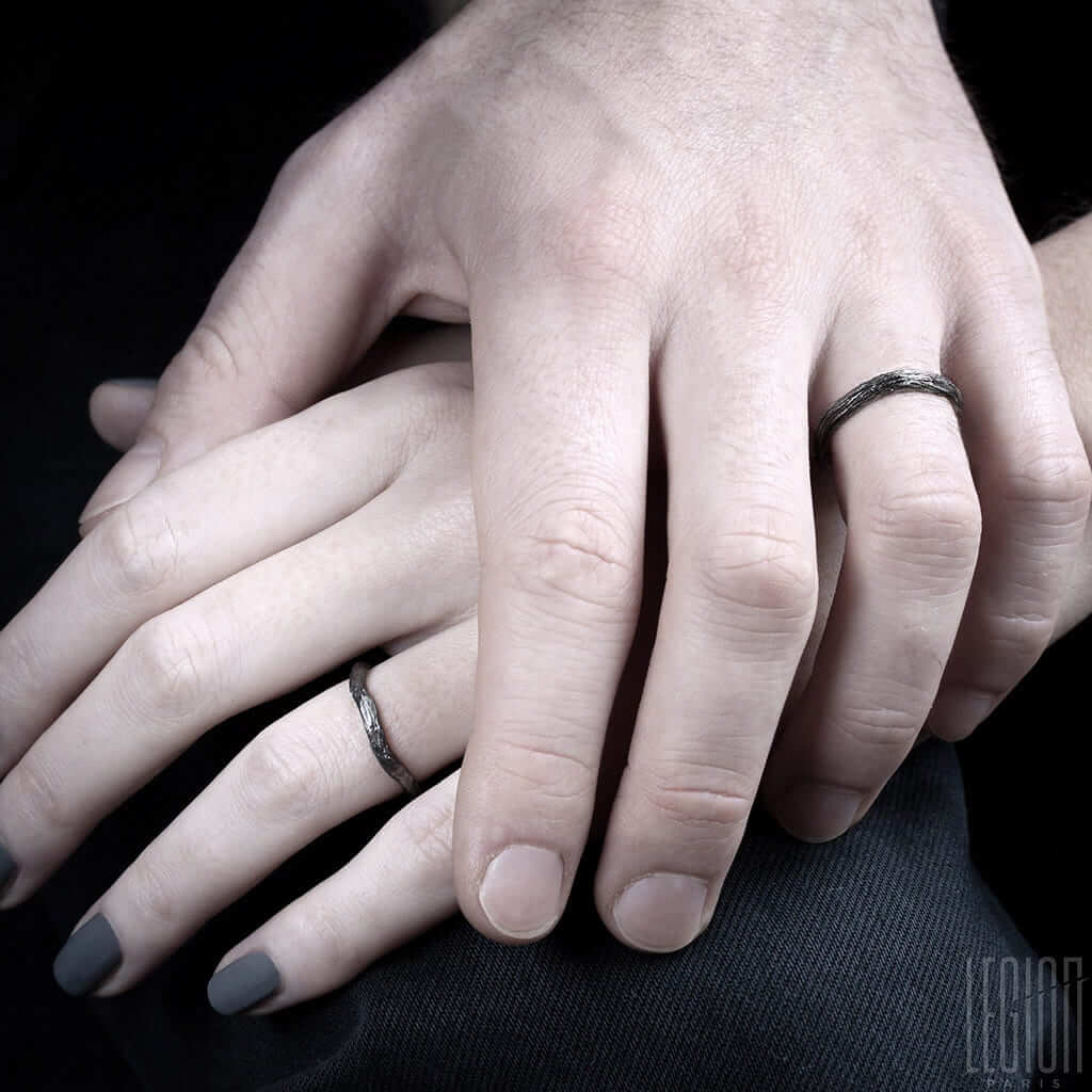 mains de femme et d'homme portant des alliances texturées en or noir