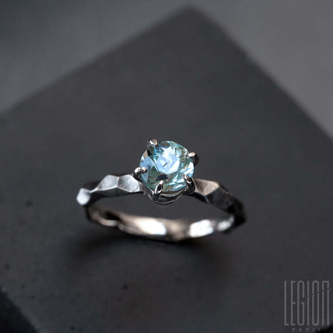 bague solitaire en or blanc texturée avec une pierre aigue marine bleue