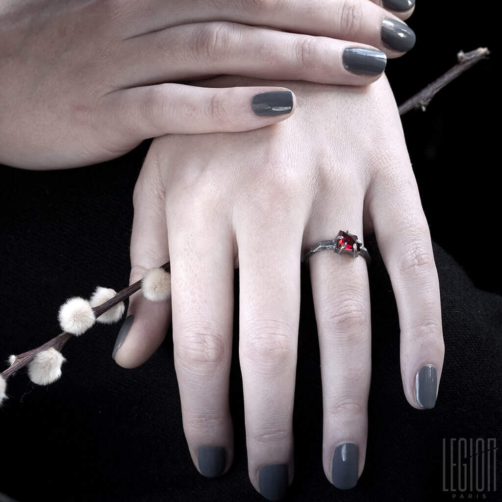 mains de femme portant une bague solitaire avec une pierre rouge grenat