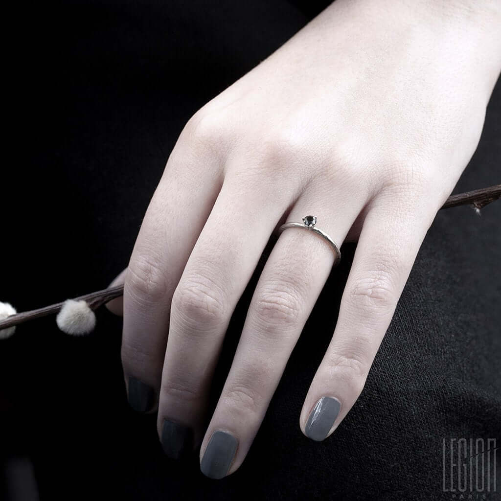 main de femme portant un solitaire en or blanc avec un diamant noir
