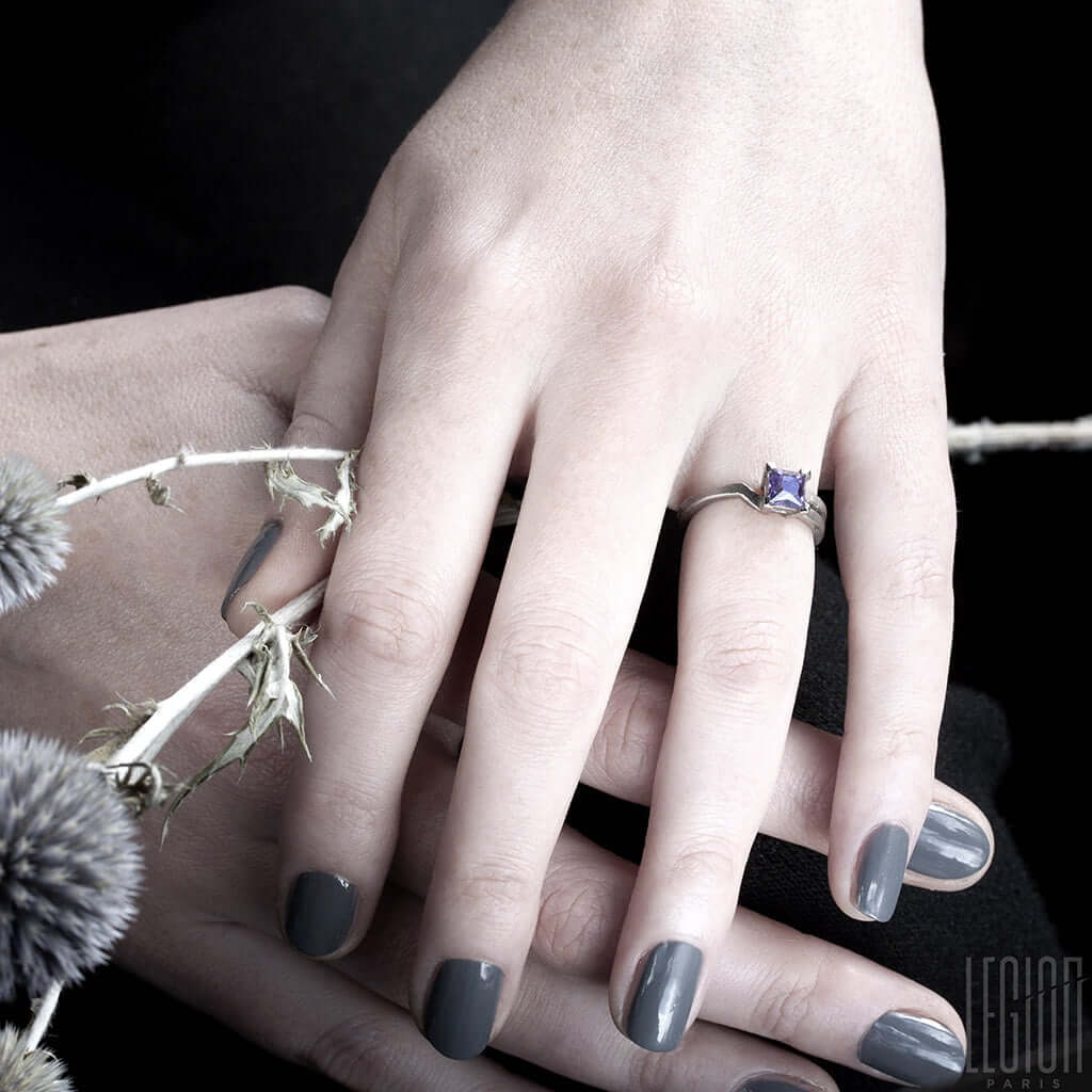 mains de femme portant une bague de fiançailles en or blanc avec une pierre violette