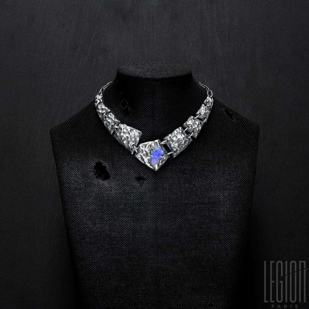 Buste noir en tissus sur lequel se trouve un collier plastron en argent noir fait de différentes tuiles texturées en argent noir avec au centre un opale noire brute