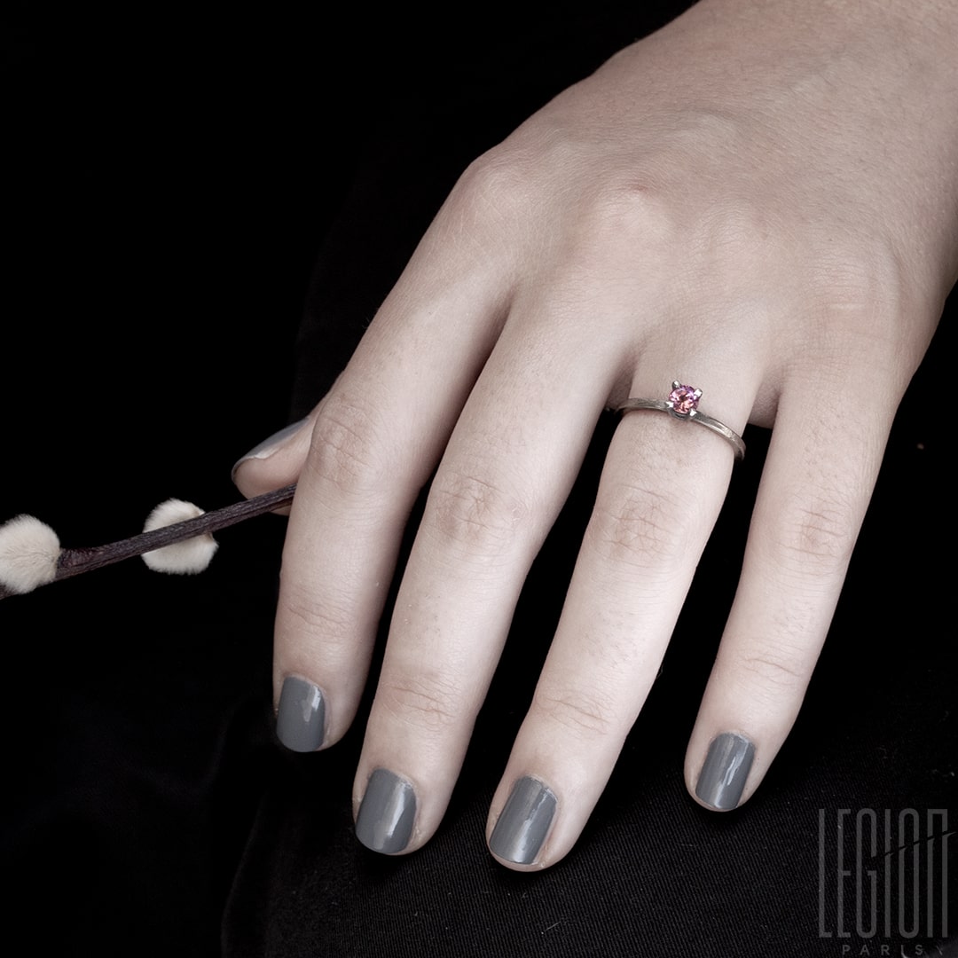 main de femme portant une bague solitaire en or blanc legerement martelé avec une tourmaline rose ronde