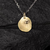 yellow gold medal with a champagne diamond on a black silver chain