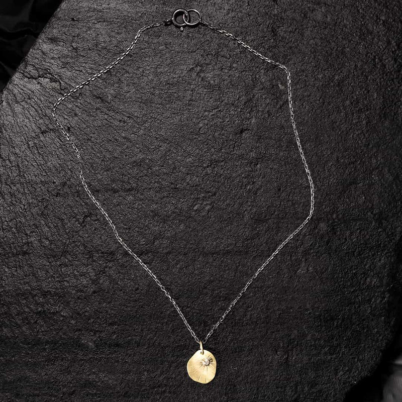 yellow gold medal with a champagne diamond on a black silver chain