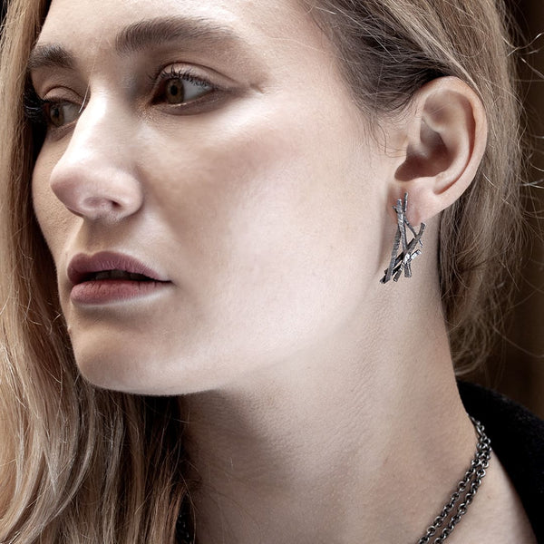 jeune femme portant une boucle d'oreille en argent noir faites de brindilles asymétriques