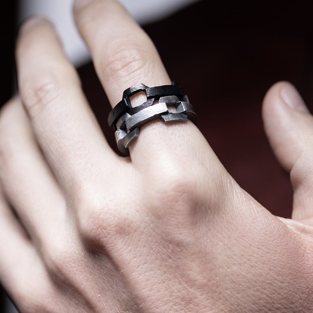 main d'homme portant un ensemble de bagues originales en argent noir