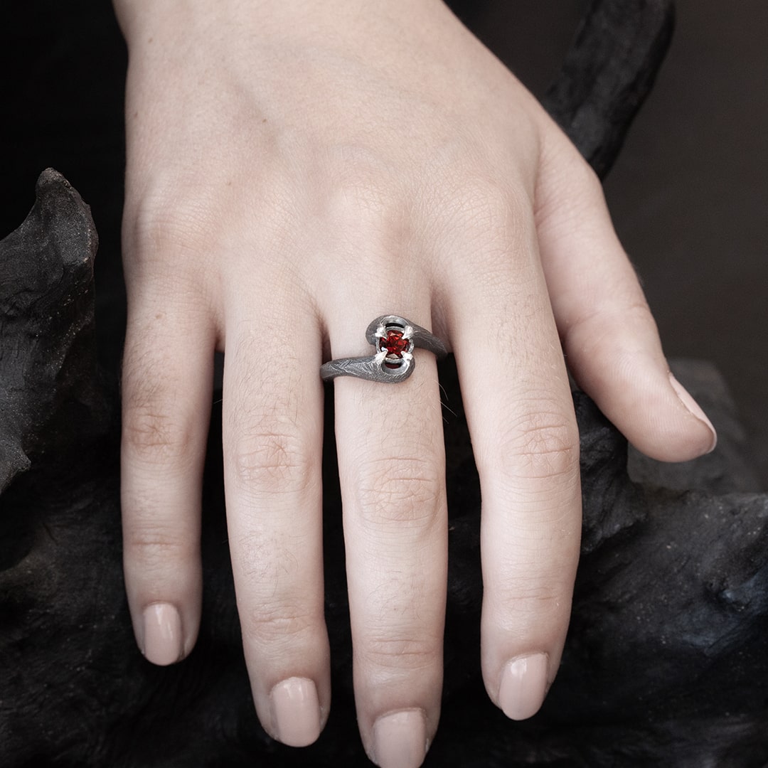 main de femme portant une bague originale en argent et grenat rouge 
