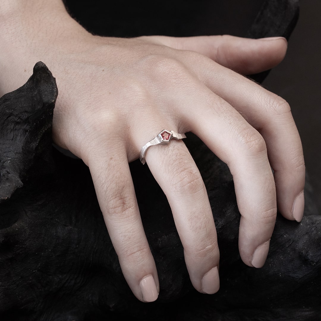 main de femme portant une bague originale en or blanc avec pierre spinelle rose
