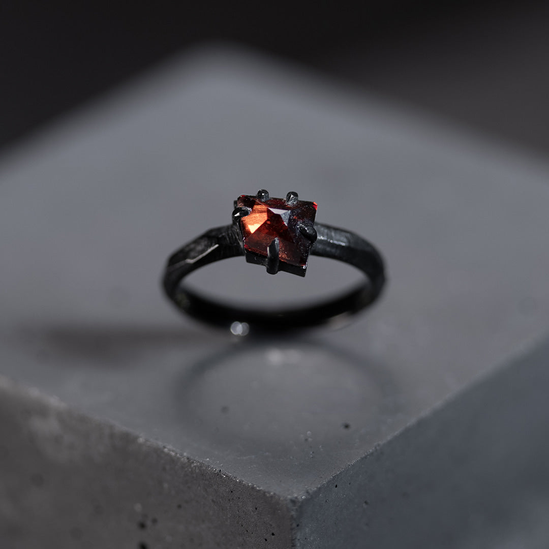 bague de fiançailles en or noir avec un grenat rouge