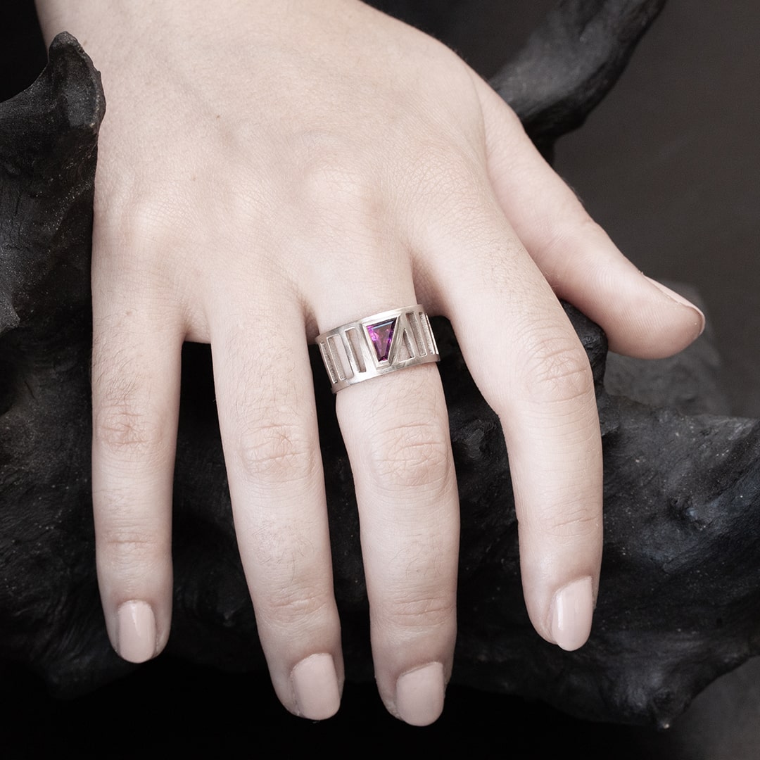 main de femme portant une bague pour femme large en or blanc avec une pierre rose