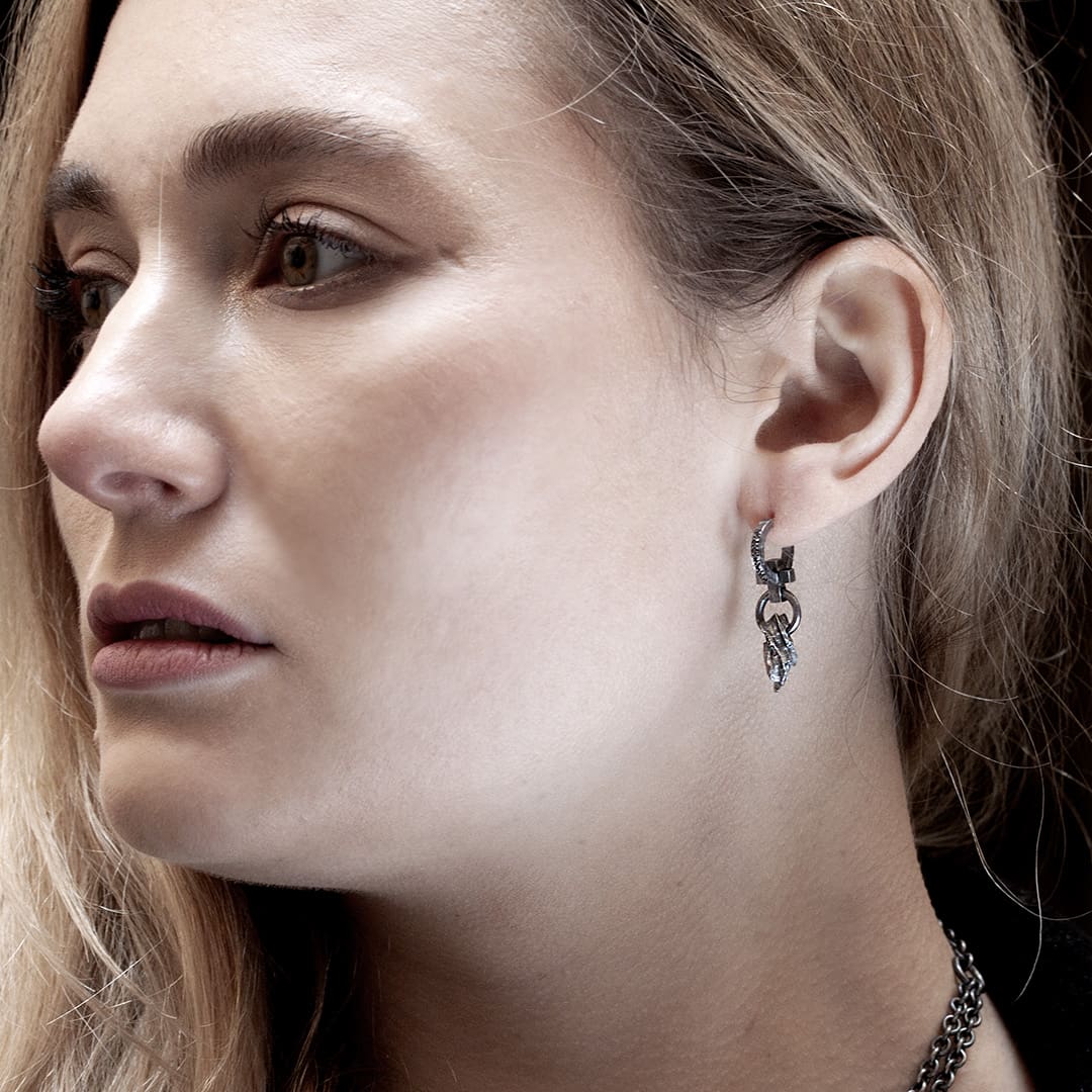 jeunne femme blonde portant une boucle d'oreille en argent noir et diamants noirs