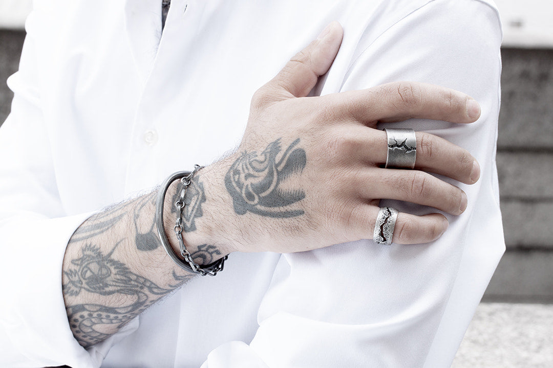 main homme tatoué portant bijoux argent