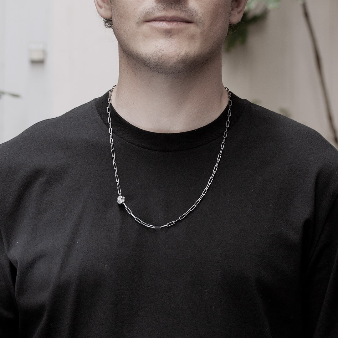 homme portant un collier original en argent avec un tête de mort et deux diamants noirs
