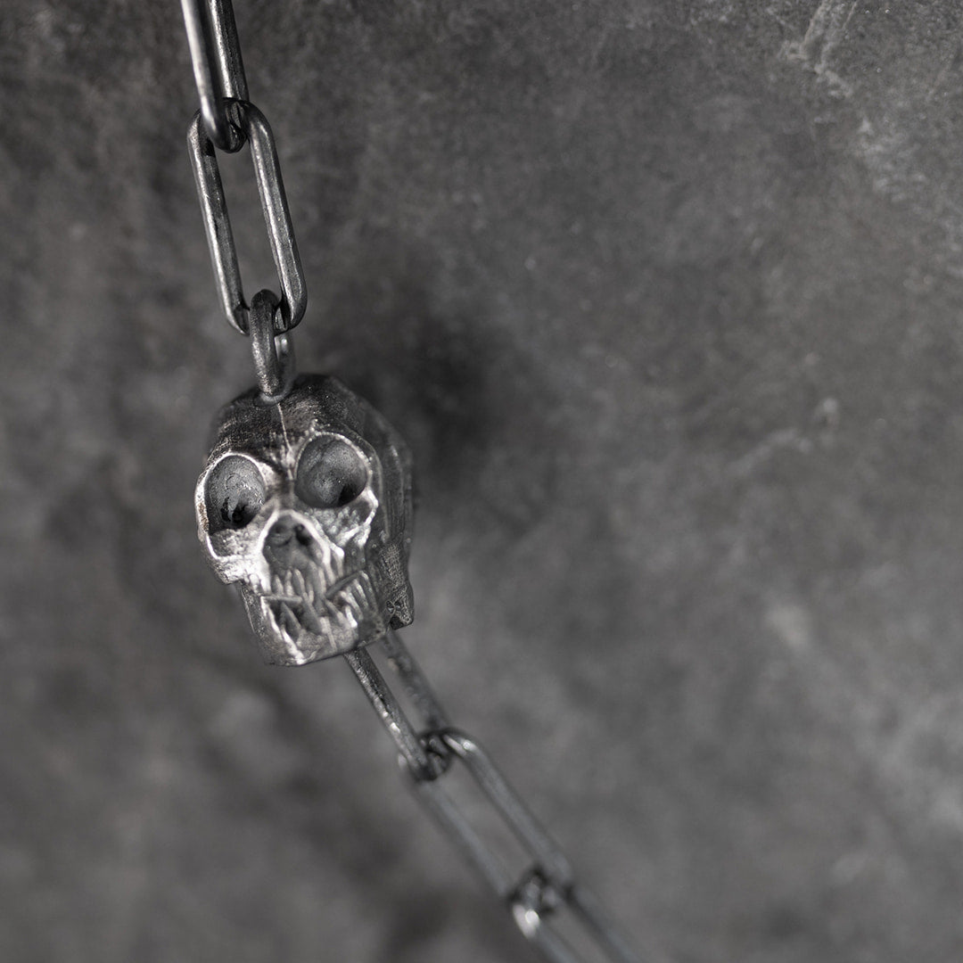 collier original en argent avec un tête de mort et deux diamants noirs