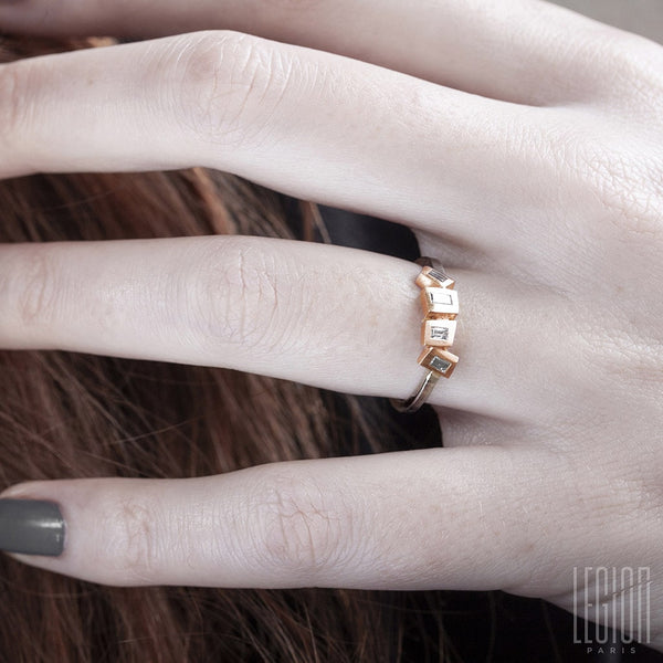 main de femme portant une bague en or blanc et rouge avec des diamants rectangle