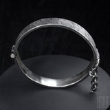 vue de côté d'un bracelet rigide en argent noir avec une goupille