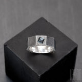 anneau facetté, texturé comme un ecrou en argent noir avec une pierre bleue carrée sertie dans le métal
