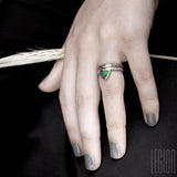 main de femme portant deux bagues en or blanc. Une alliance facetée et une bague composée d'un anneau texturé et d'une opale noire avec des feux vert et orange sertie en clos sur le dessus 