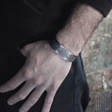 main d'homme habillé en noir portant un bracelet large en argent avec un dessin gravé sur le dessusBRACELET MANCHETTE LARGE EN ARGENT GRAVÉ