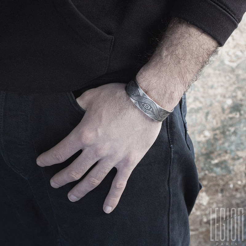Main d'homme portant un bracelet en argent noir avec une gravure d'oeil sur le dessus