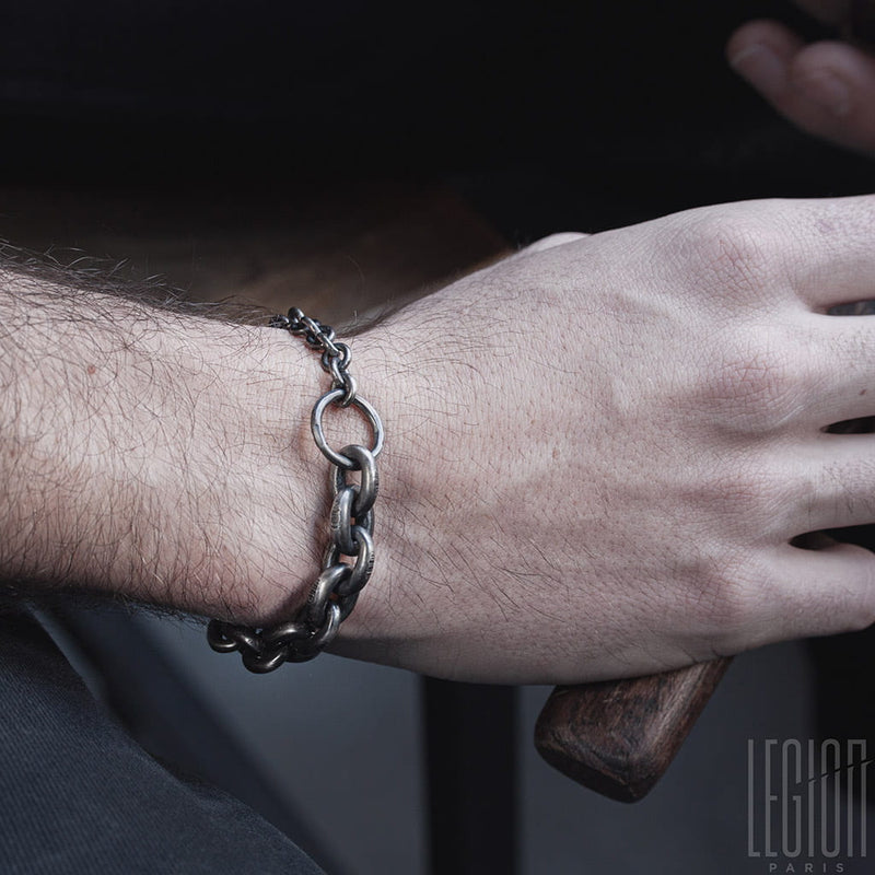 poignet d'homme portant un bracelet en chaine en argent noir avec des gros maillons et un anneau
