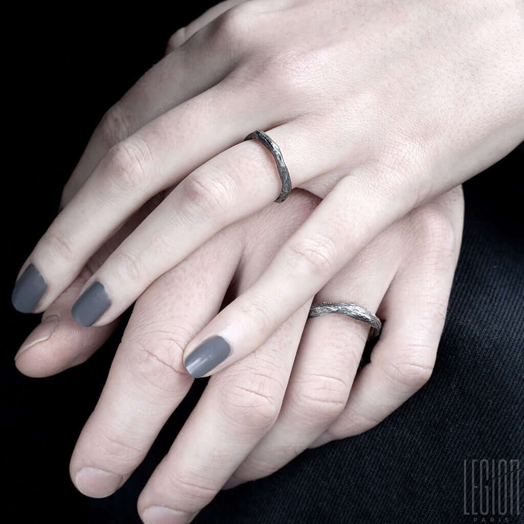 mains de femme et d'homme portant des alliances texturées en argent noir
