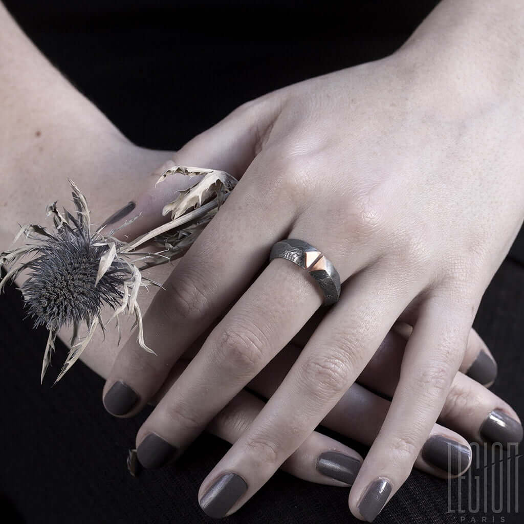 mains de femme portant une bague en argent noir texturé et or rouge