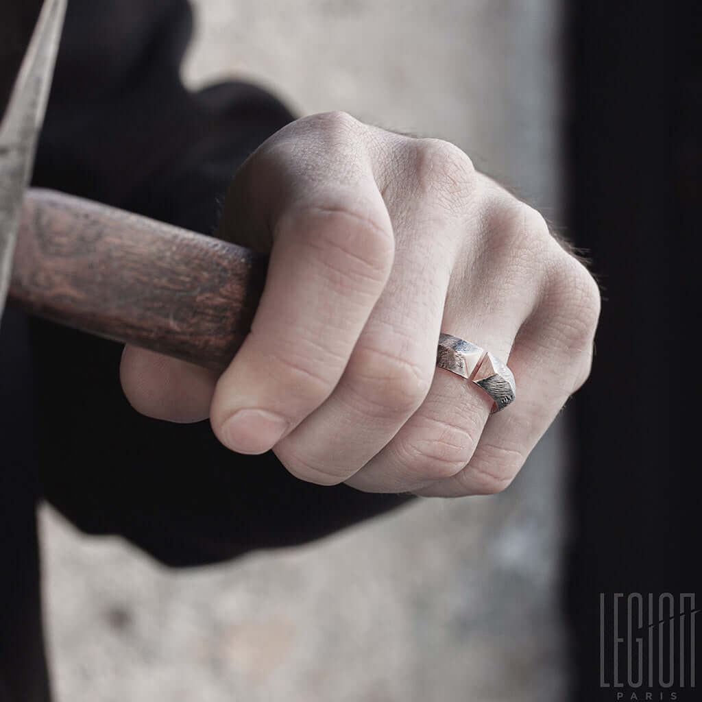 mains d'homme portant une bague ouverte en argent noir texturé et or rouge