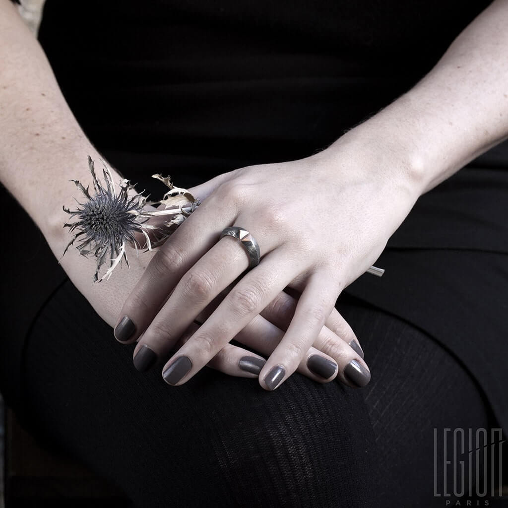 mains de femme avec des ongles gris portant une bague ouverte en argent noir et or rouge