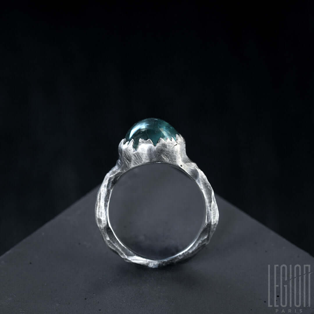 vue de côté d'une bague Legion Paris en argent noir 925 avec un serti dentelé sur une pierre bleue indicolite