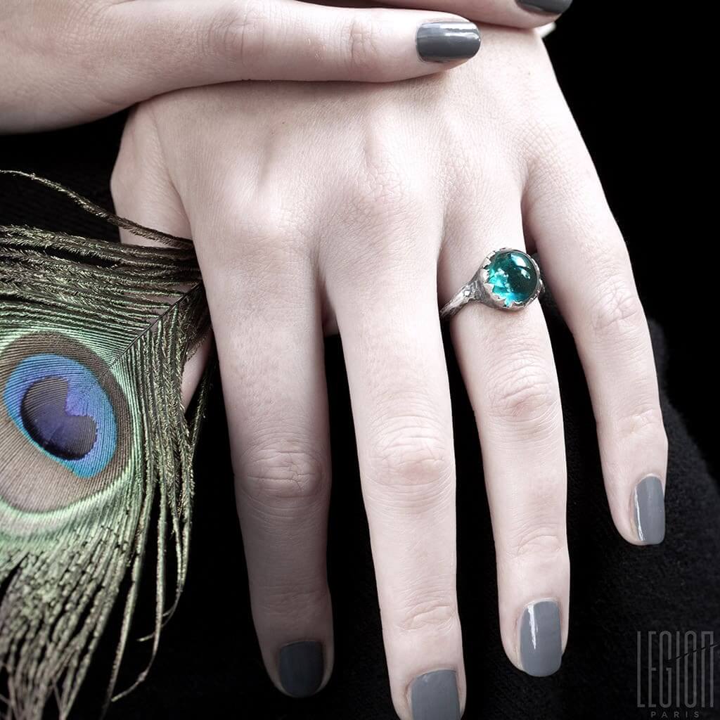 mains de femme portant une bague en argent avec une tourmaline bleue
