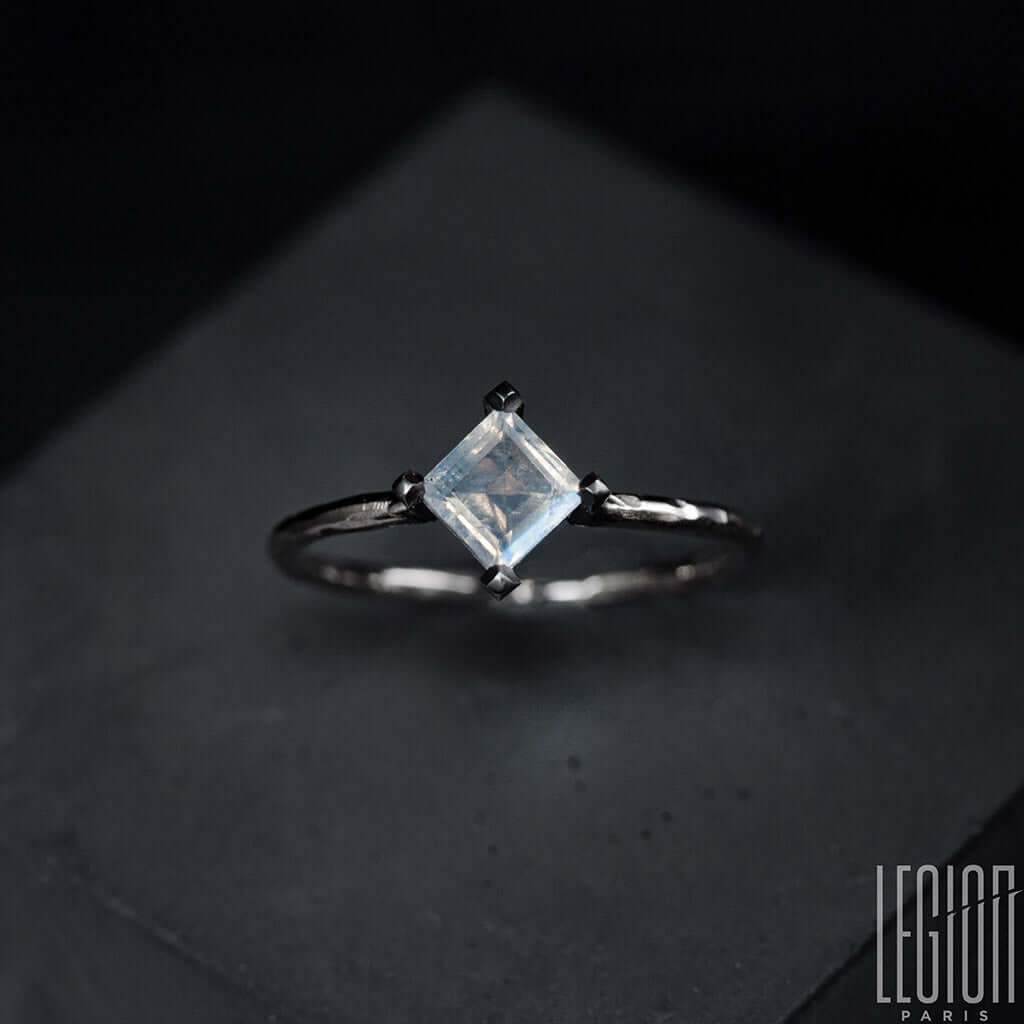 gros plan sur une pierre de lune carrée avec un corps dde bague en or blanc