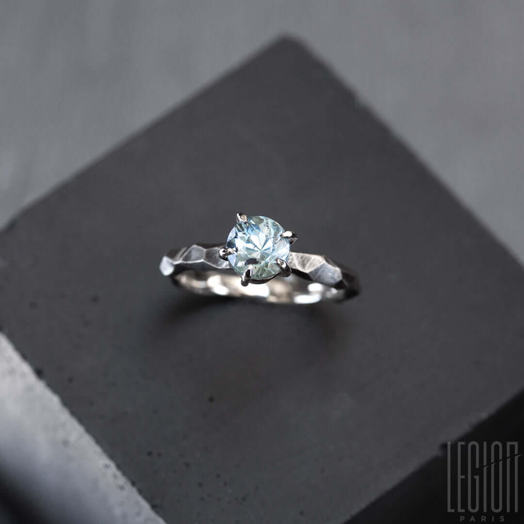 bague solitaire en or blanc texturée avec une pierre aigue marine bleue