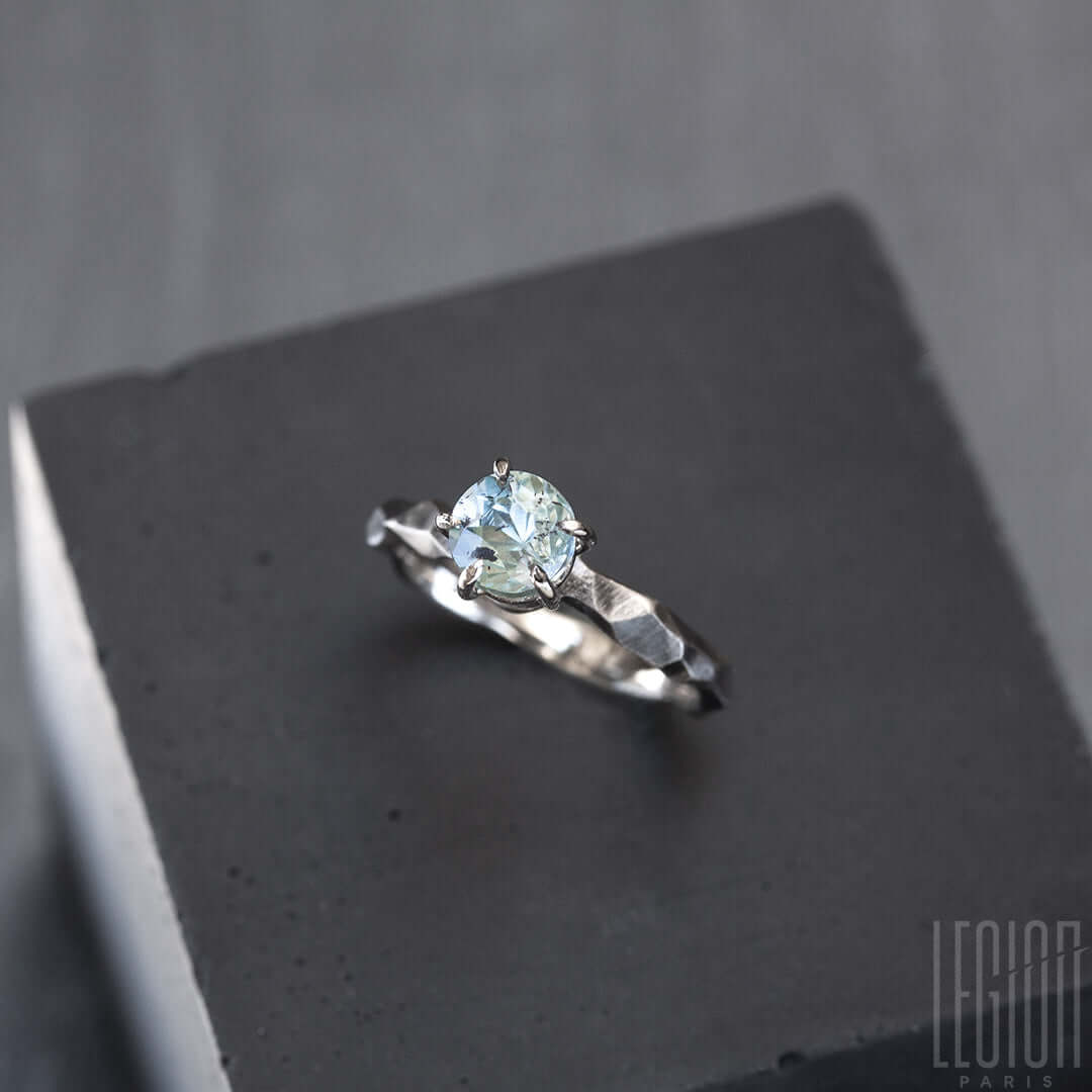 bague solitaire en or blanc texturée avec une pierre aigue marine bleue
