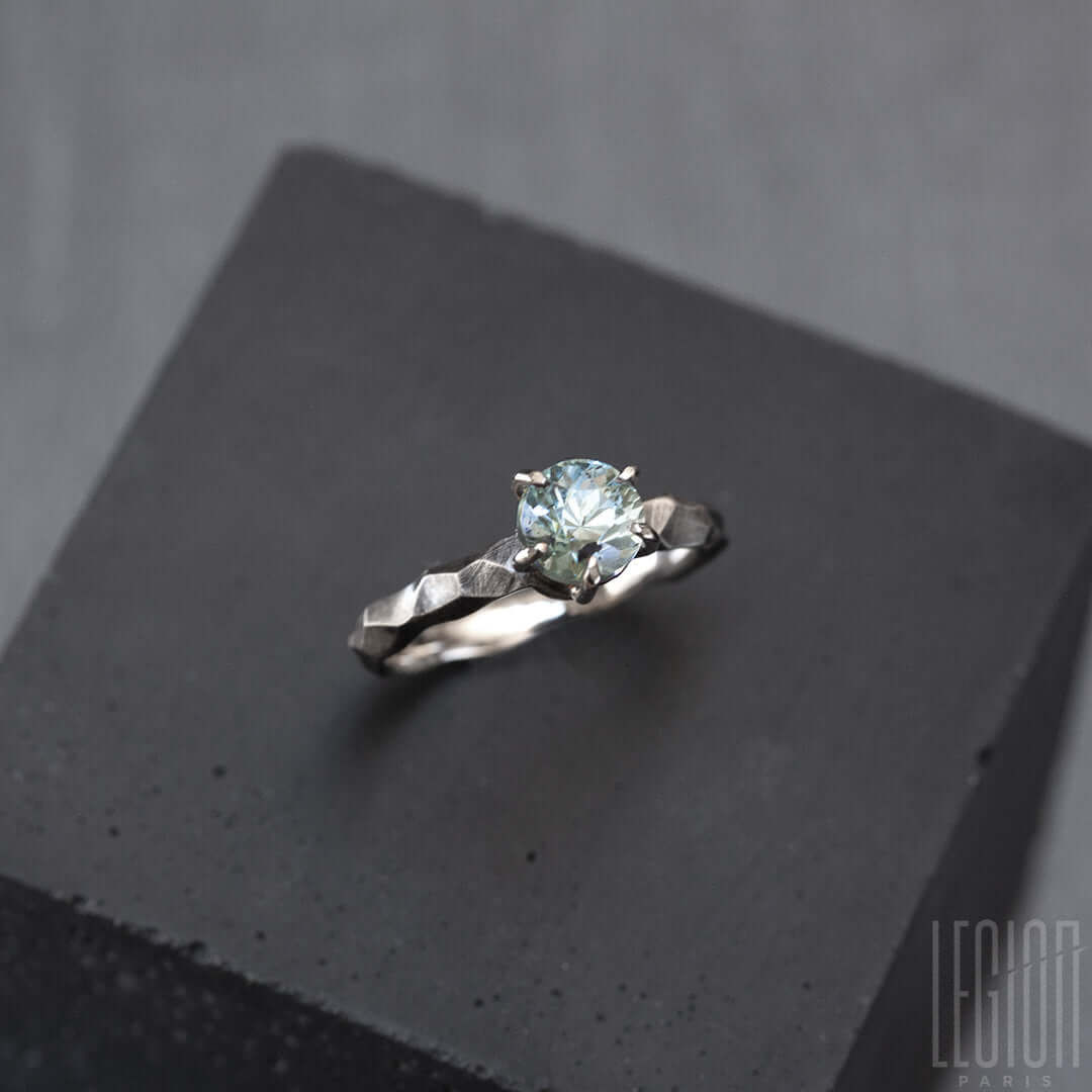 vue de côté d'une bague solitaire en or blanc texturée avec une pierre aigue marine bleue