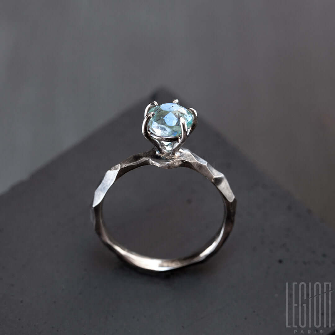 vue de face d'une bague solitaire en or blanc texturée avec une pierre aigue marine bleue sertie avec des griffes en or blanc