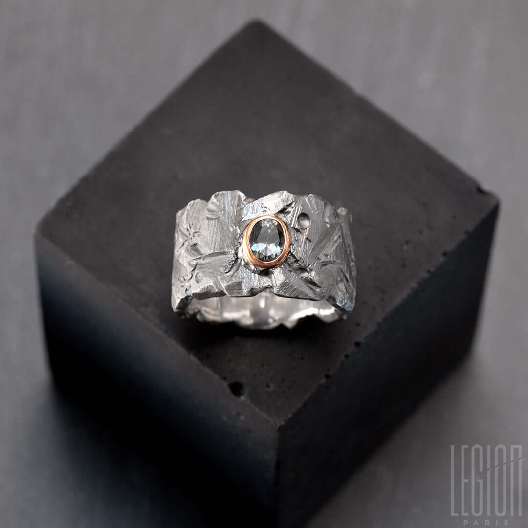 bague très large en argent noir texturé avec une pierre ovale, un spinelle gris vert, serti en clos en or rouge. 