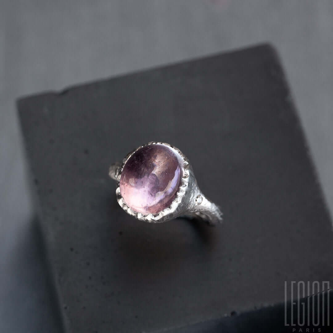 pierre ovale mauve tourmaline rose montée sur une bague en or blanc avec un serti comme dechiré