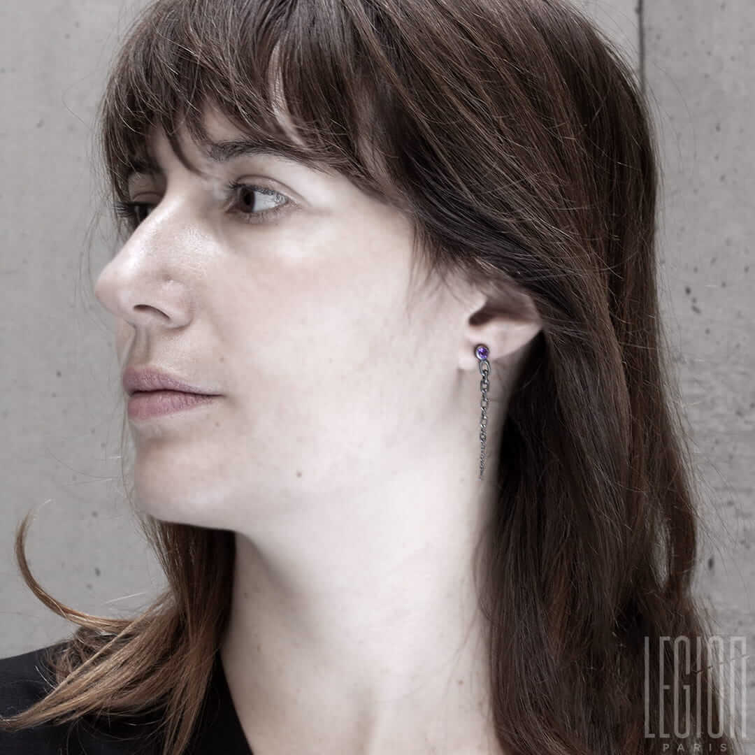 Femme blanche aux cheveux roux portant une boucle d'oreille avec une amethyste ronde et une chute de chaine en maille forçat en argent noir
