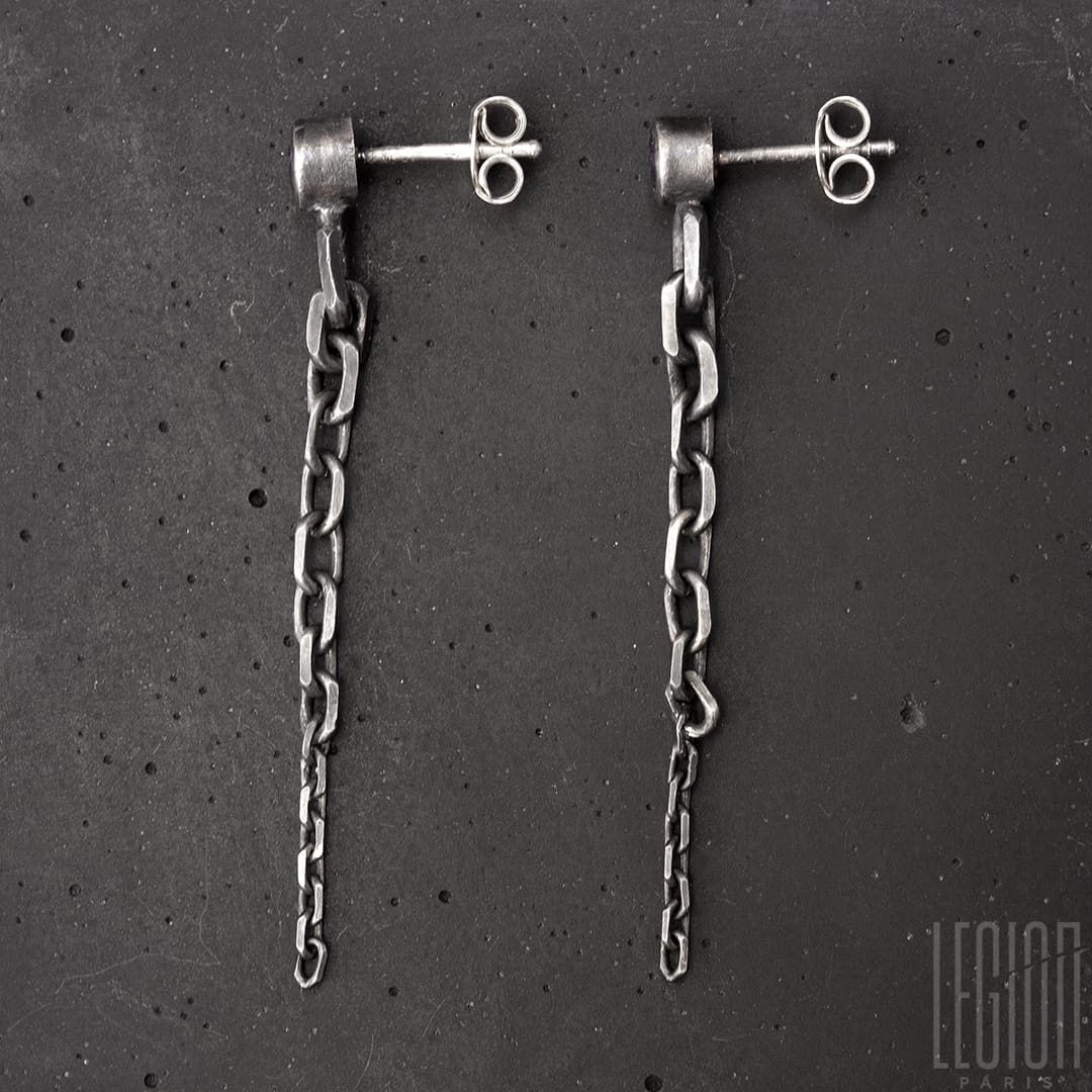 boucles d'oreilles en argent noir. chaque boucle à une pierre ronde violette sertie en clos. De cette pierre part une chute de chaine en maille forcat de la plus grosse à la plus fine