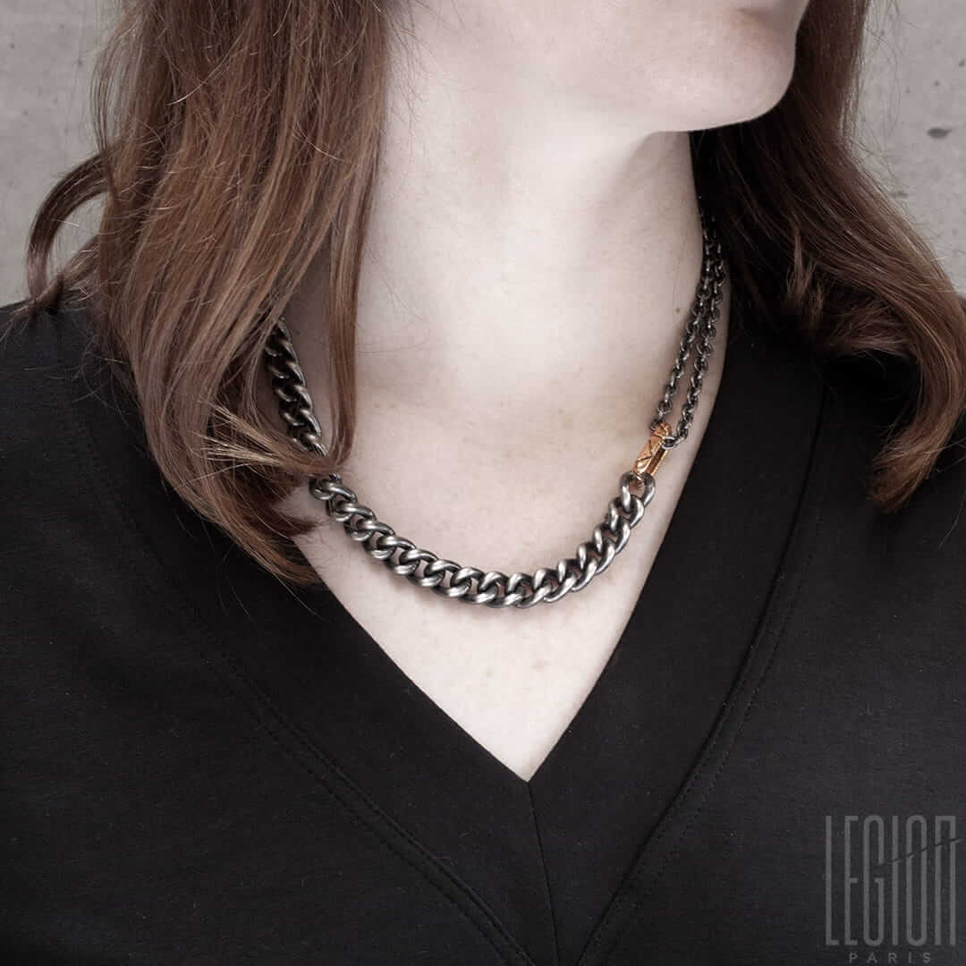 Femme rousse portant un collier massif en chaine gourmette en argent noir avec un anneau rectangulaire en or rouge dans lequel passe une double chaine forçat ronde en argent noir