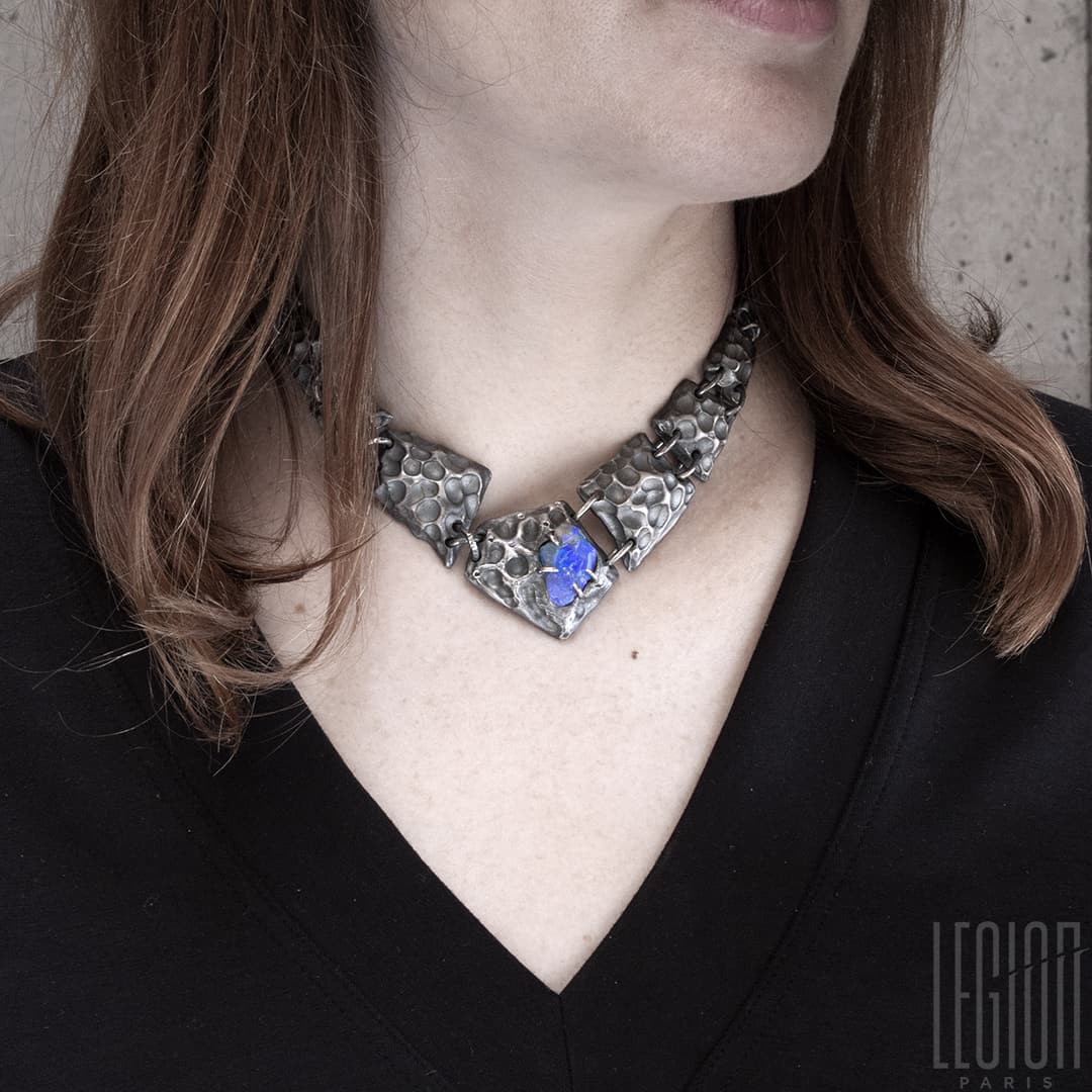 femme rousse portant un tee shirt noir et un collier plastron en argent noir fait de différentes tuiles texturées en argent noir avec au centre un opale noire brute