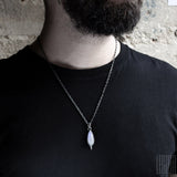 man wearing a pendant with a white moonstone 